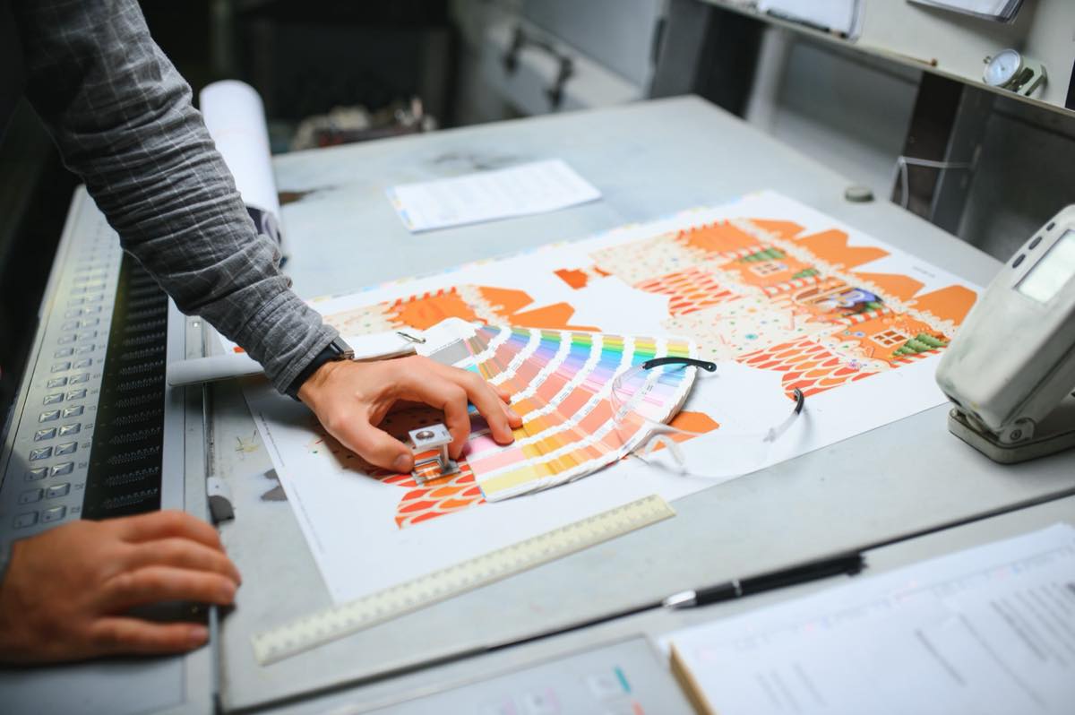 Press operator inspecting color quality on a freshly printed sheet